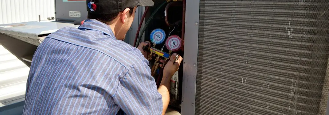 HVAC technician servicing a condenser unit in West New York